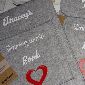 May include: Two gray felt bags with a white heart and the text "Slimming World Book" on the front. The bags have a brown tag that says "Wear Don't Waste" and "BagBase".