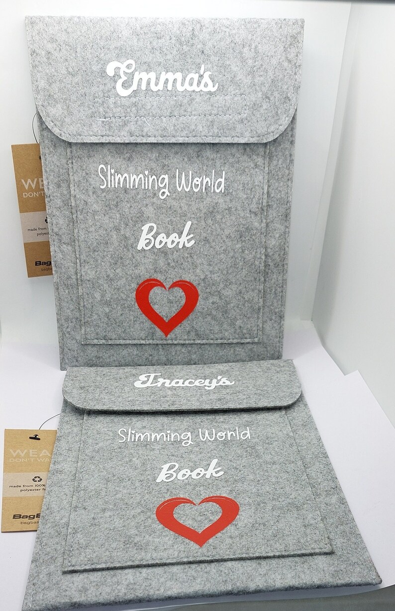 May include: Two gray felt book covers with white text and a red heart. The top cover says "Emma's Slimming World Book" and the bottom cover says "Tracey's Slimming World Book".