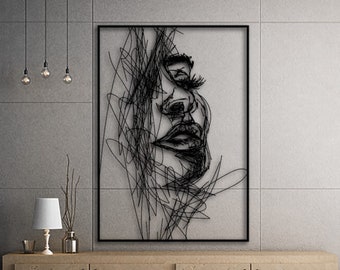 May include: Black and white line art wall decor featuring a woman's face. The artwork is framed in a black frame and is hanging on a gray wall above a wooden cabinet.