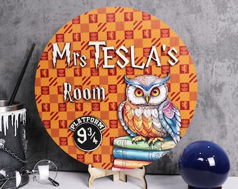 May include: A round wooden sign with the text "Mrs Tesla's Room" and an owl illustration. The sign has a patterned background in orange and red. The owl is perched on a stack of books.
