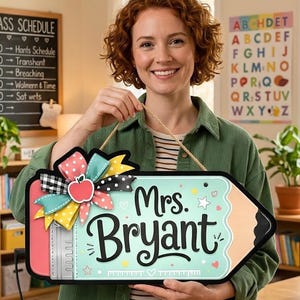 May include: A pencil-shaped wooden sign with a light blue background, featuring the text 'Mrs. Bryant' in black script, a red apple icon, and a decorative multi-colored ribbon bow. The sign includes a ruler graphic and hangs from a jute rope.