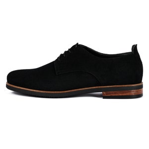May include: Black suede leather lace-up shoes with a brown leather sole.