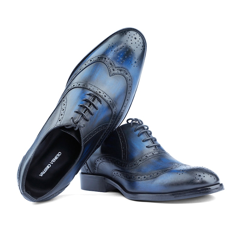 Puede incluir: Un par de zapatos Oxford de cuero azul con detalles de punta de ala y cierre de cordones. Los zapatos tienen un aspecto desgastado y el nombre de la marca "VALERO VENETO" es visible en la plantilla.