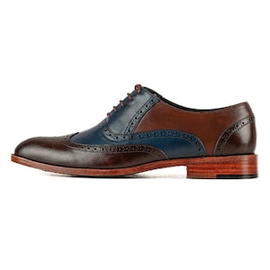 Op de afbeelding: Bruine en blauwe leren oxfords met een wingtip-ontwerp en een vetersluiting.