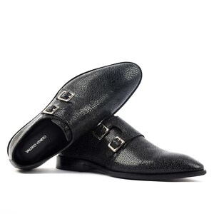 K&ouml;nnte beinhalten: Schwarze Doppel-Monk-Schuhe aus Leder mit strukturierter Oberfl&auml;che. Die Schuhe haben silberne Schnallen und der Markenname "VALERIO VENETO" ist seitlich aufgedruckt.