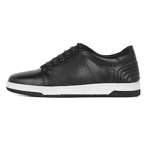 May include: Black leather sneakers with white soles. The shoes have a classic lace-up design, a padded collar, and decorative stitching on the heel. The soles are approximately 1 inch thick.