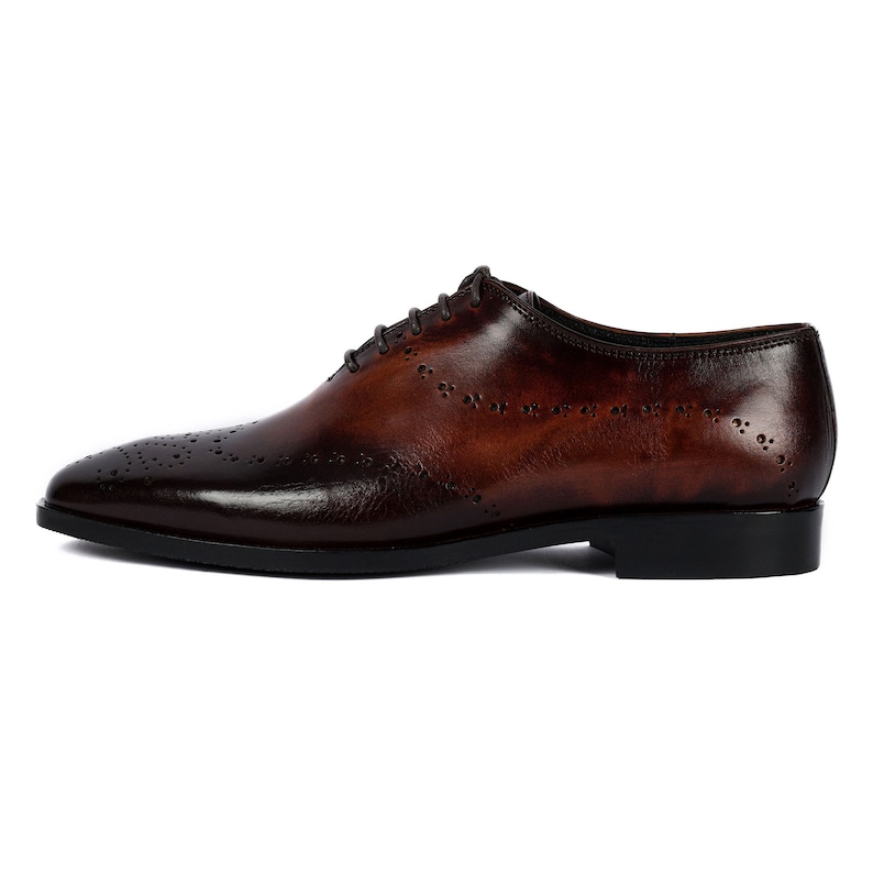 May include: Brown leather oxford shoes with a wingtip design and a lace-up closure.