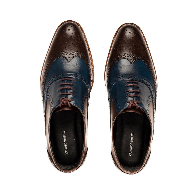 Op de afbeelding: Een paar bruine en blauwe leren veterschoenen met wingtip details. De schoenen hebben een bruin leren bovenwerk met een blauwe leren neus en een bruine leren hak. De schoenen zijn gelabeld "VALENTINO VENETO" en "GIUSEPPE CREATIVA".