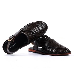 May include: A pair of brown leather sandals with a woven design and a buckle fastening. The sandals have a pointed toe and a flat sole. The brand name "VALERO VENETO" is printed on the strap.