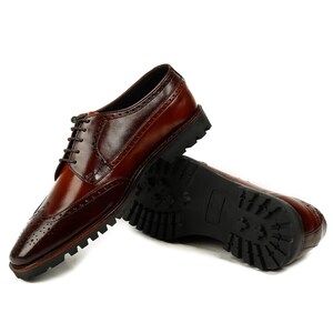 Pu&ograve; includere: Scarpe brogue in pelle marrone con punta a ala e suola in gomma nera.