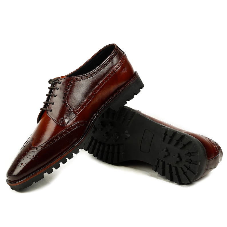 Pu&ograve; includere: Scarpe brogue in pelle marrone con punta a ala e suola in gomma nera.