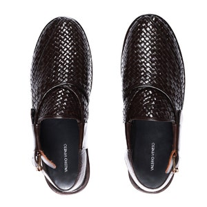 May include: A pair of brown leather woven slip-on shoes with a buckle detail. The shoes have the brand name "VALERIO VENETO" printed on the inside.