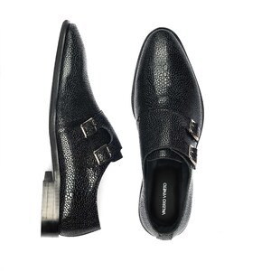 K&ouml;nnte beinhalten: Schwarze Lederschuhe mit doppeltem M&ouml;nchriemen, texturierter Oberfl&auml;che und silbernen Schnallen. Die Schuhe tragen den Markennamen "VALERIO VENETO", der auf der Innenseite aufgedruckt ist.