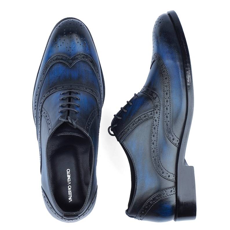 Puede incluir: Un par de zapatos de vestir de cuero azul y negro con dise&ntilde;o de punta de ala. Los zapatos tienen cierre de cordones y suela texturizada. El nombre de la marca "VALENTINO VENETO" est&aacute; impreso en el interior del zapato.