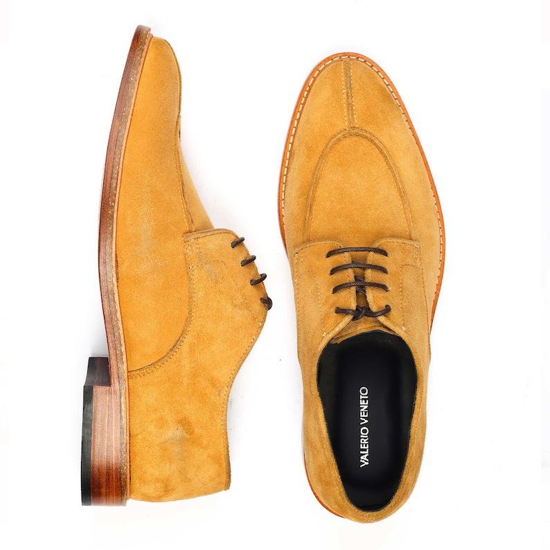 May include: Mustard-coloured suede dress shoes with brown laces. The shoes feature a classic design with a rounded toe and stitched sole. The brand name "VALERIO VENETO" is visible on the insole. The shoes are displayed against a white background.