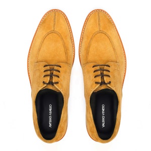 May include: Mustard-coloured suede dress shoes with brown laces, a rounded toe, and a stitched sole. The shoes have the words "VALERIO VENETO" printed on the insole.