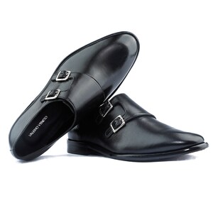May include: A pair of black leather dress shoes with double monk straps and silver buckles. The shoes have a sleek, polished appearance and the brand name "VALERIO VENETO" is visible on the inner sole.