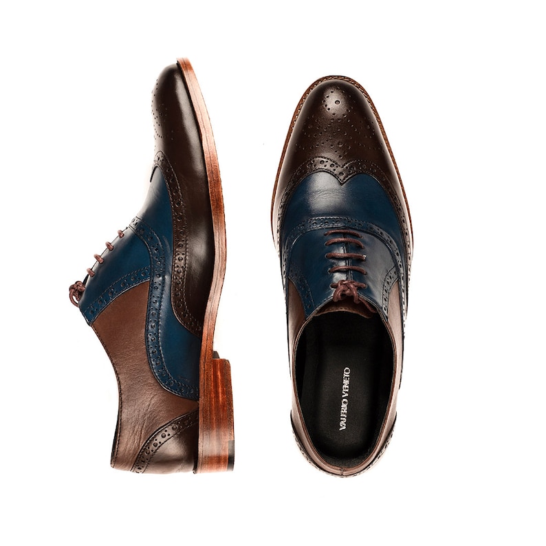 Op de afbeelding: Een paar bruine en blauwe leren veterschoenen met wingtip details. De schoenen hebben een bruine leren zool en een bruine leren hak. De merknaam "Valfredo Vineto" staat gedrukt aan de binnenkant van de schoen.