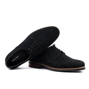 May include: Black suede leather lace-up shoes with a brown leather sole. The shoes are laid out on a white background. The brand name "VALERIO VENETO" is visible on the inside of one shoe.