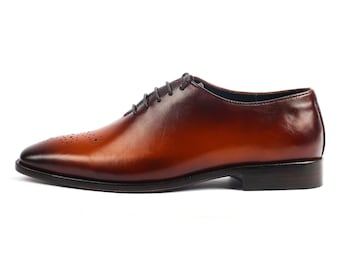 Könnte beinhalten: Ein Paar braune Lederschnürschuhe mit einem dezenten Ombre-Effekt. Die Schuhe haben eine spitze Zehenpartie und eine geschlossene Schnürung.