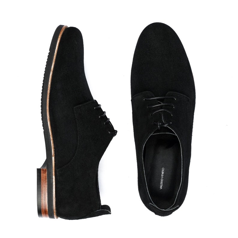 May include: A pair of black suede lace-up shoes with brown leather trim. The shoes have a simple design and are made of high-quality materials.