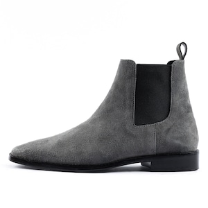 May include: Grey suede Chelsea boots with a black elastic panel and a black rubber sole.