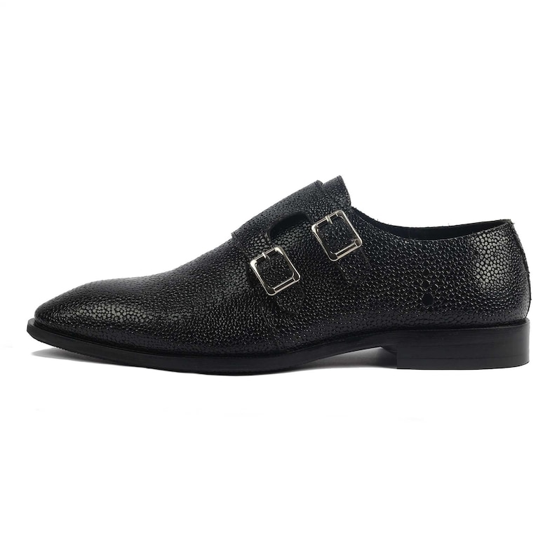 K&ouml;nnte beinhalten: Schwarze Lederschuhe mit doppelten Schnallen. Die Schuhe haben eine strukturierte, genarbte Oberfl&auml;che.