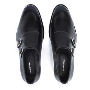 May include: A pair of black leather double monk strap shoes. The shoes have silver-colored buckles and the brand name "VALERIO VENETO" is printed on the insole. The shoes are shown from a top-down perspective.