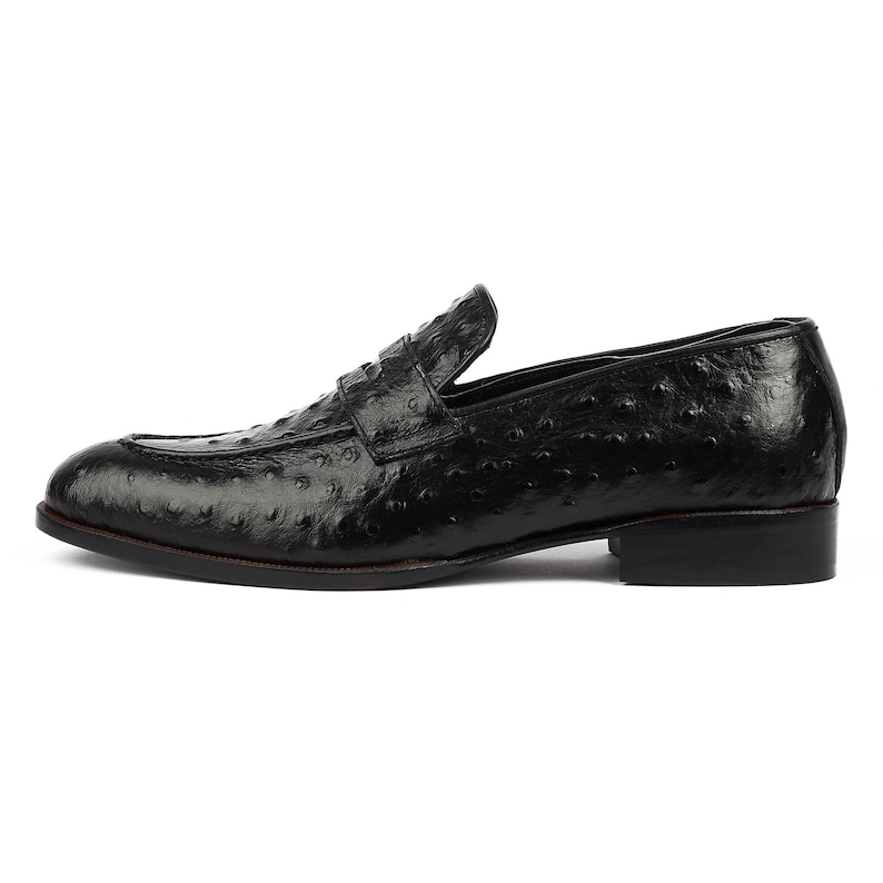 May include: Black leather loafers with an ostrich print pattern.