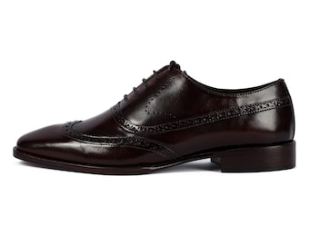 Puede incluir: Un par de zapatos de cuero marrón con cordones y detalles de punta de ala. Los zapatos tienen un diseño clásico de brogue y un acabado pulido.