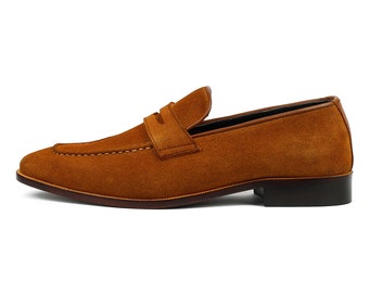 May include: A pair of brown suede leather loafers with a penny strap detail.