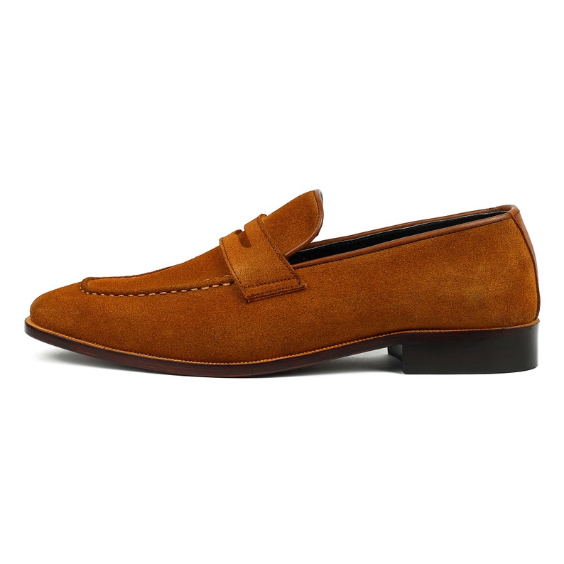 May include: A pair of brown suede leather loafers with a penny strap detail.