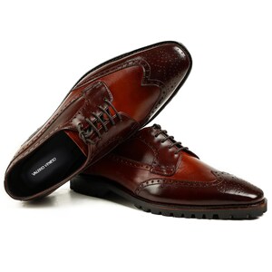 Pu&ograve; includere: Scarpe stringate in pelle marrone con punta a ala e chiusura con lacci. Le scarpe hanno una suola testurizzata e il nome del marchio "VALERIO VENETO" &egrave; visibile sulla soletta.