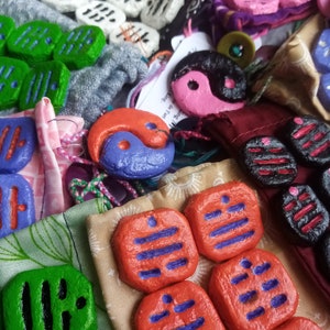 Può includere: Assortimento di pezzi da gioco in legno dipinti a mano di vari colori, con diversi simboli e disegni. I pezzi sono di vari colori, tra cui verde, rosso, nero, bianco e rosa. Alcune delle pedine hanno un simbolo yin-yang, mentre altre hanno strisce o altri motivi geometrici.
