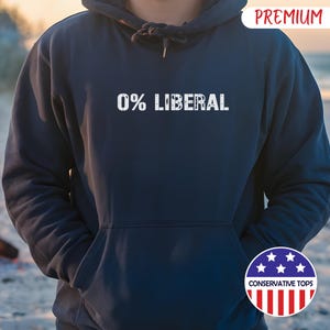 May include: Navy blue hooded sweatshirt with the text "0% LIBERAL" in white block letters. The sweatshirt has a front pocket and a drawstring hood. The word "PREMIUM" is in a red box in the upper right corner. The bottom right corner has a logo that says "CONSERVATIVE TOPS".