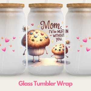 May include: A set of three white glass tumblers with a wood lid and a straw. The tumblers are decorated with a pink and white heart pattern, a cartoon cupcake with a pink frosting and sprinkles, and the text "Mom, I'd be mufin without you."