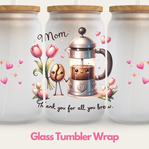 May include: A white glass tumbler with a wood lid and a straw. The tumbler has a design of a cartoon coffee pot with a smiling face, a coffee bean, and pink flowers. The text "Mom" and "Thank you for all you brew" are printed on the tumbler.