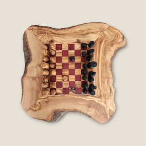 May include: A wooden chessboard set with black and white pieces on a natural wood base. The board has a red and brown checkered pattern.