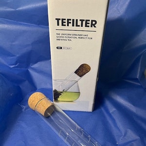 May include: A clear glass tube with a cork stopper and markings. The tube is labelled "TEFILTER" and says "The uniform strainer has good filtration, perfect for brewing tea." The box also says "SIZE 3 x 13cm".