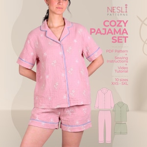May include: Pink pajama set with a floral pattern, featuring a button-down shirt and shorts. The set has light blue trim and is made of a soft, textured fabric. The image includes the text "COZY PAJAMA SET" and "NESLI PATTERNS".