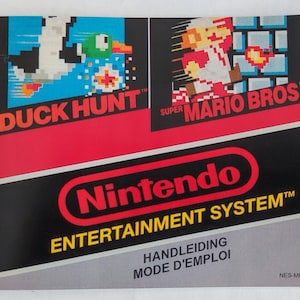 Peut inclure: Un manuel de jeu Nintendo Entertainment System vintage avec Duck Hunt et Super Mario Bros. La couverture est rouge, noire et grise, avec le logo Nintendo. Le manuel comprend le texte "HANDLEIDING" et "MODE D'EMPLOI".