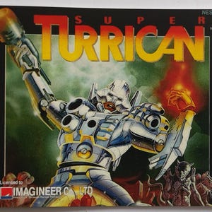 Peut inclure: Une cartouche de jeu vidéo pour le jeu Super Turrican, mettant en scène un robot argenté tenant une arme et une explosion d'énergie rouge. La cartouche est sous licence Imagineer Co. Ltd. et est étiquetée NES-TU-FRA.