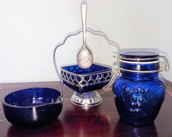 Peut inclure: Ensemble de pièces de service en verre bleu cobalt. Comprend un petit plat ovale, un plat carré avec un cadre et une cuillère en filigrane argenté, et un pot avec un couvercle à charnière. Le pot a un motif de raisin.