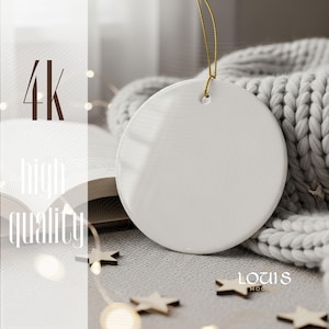 May include: A blank, white ceramic ornament with a gold string for hanging. The ornament is round and smooth, with a glossy finish. The background includes a gray knitted blanket, wooden star decorations, and the text "4k high quality".