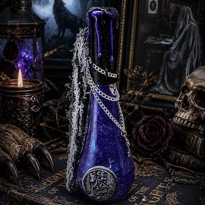 May include: A glass bottle filled with a shimmering purple liquid, featuring a black wax-dipped neck, silver chain accents, and a circular silver medallion depicting a wolf. The bottle is adorned with a textured black and white fringe trim.