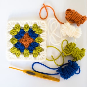 May include: A white crochet square with a colourful granny square pattern in the centre. The square is surrounded by balls of yarn in various colours, including orange, white, green, blue, and a crochet hook.