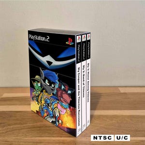 Puede incluir: Un conjunto de tres cajas de juegos de PlayStation 2. La caja principal presenta el juego "Sly Cooper and the Thievius Raccoonus" con una colorida ilustración de dibujos animados. Las lomos muestran los títulos de la serie Sly Cooper. La esquina inferior derecha dice "NTSC U/C".