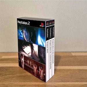 Peut inclure: Un coffret de jeux PlayStation 2 comprenant trois titres : Project Zero, Project Zero II: Crimson Butterfly et Project Zero 3: The Tormented. La couverture présente des portraits de personnages sombres et des silhouettes en robes blanches sur fond noir.