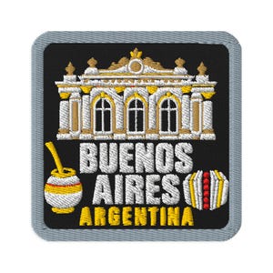 Può includere: Una toppa ricamata quadrata con bordo grigio su sfondo nero. Presenta un'illustrazione di un edificio in bianco e oro sopra il testo bianco BUENOS AIRES e il testo giallo ARGENTINA. Un mate e un alfajor si trovano sui lati.