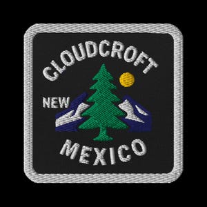 Puede incluir: Parche bordado con el texto "Cloudcroft New Mexico" en blanco, arqueado por encima y por debajo de un pino verde, un sol amarillo y montañas azules. El parche tiene un fondo negro y un borde blanco.